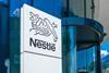 A sign with the Nestle logo against the background of a corporate building.