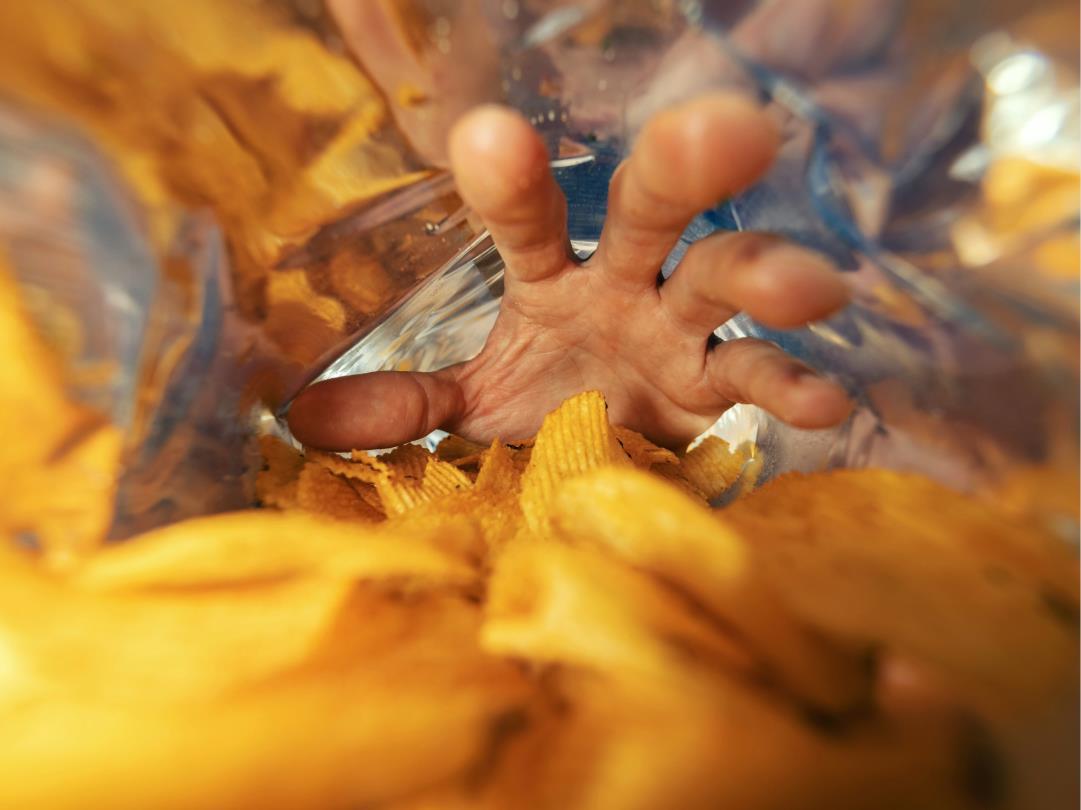 A hand reaching inside of a crisp packet