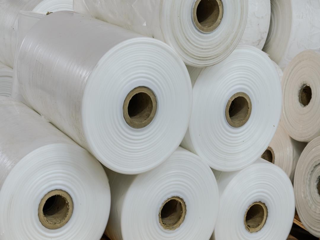 A close-up of thick rolls of polyethylene stacked on top of each other in a warehouse.
