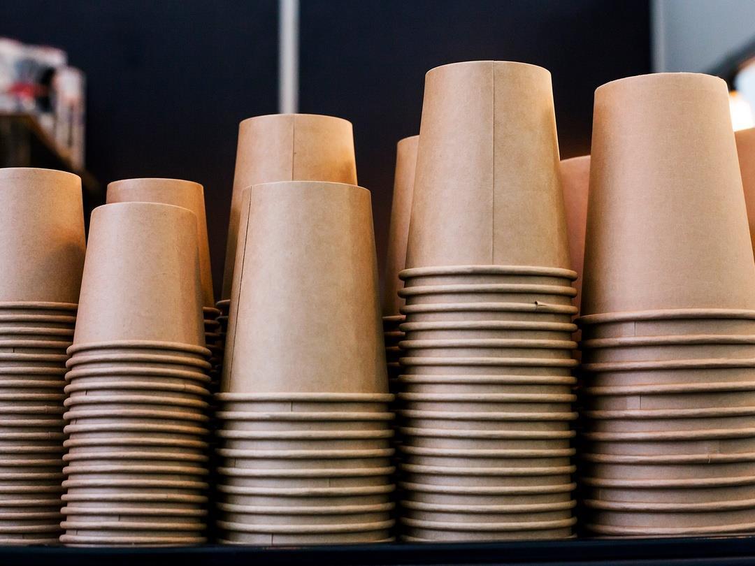 Five rows of stacked paper cups. The stacks are not even, allowing taller stacks to be seen behind the stacks in the…