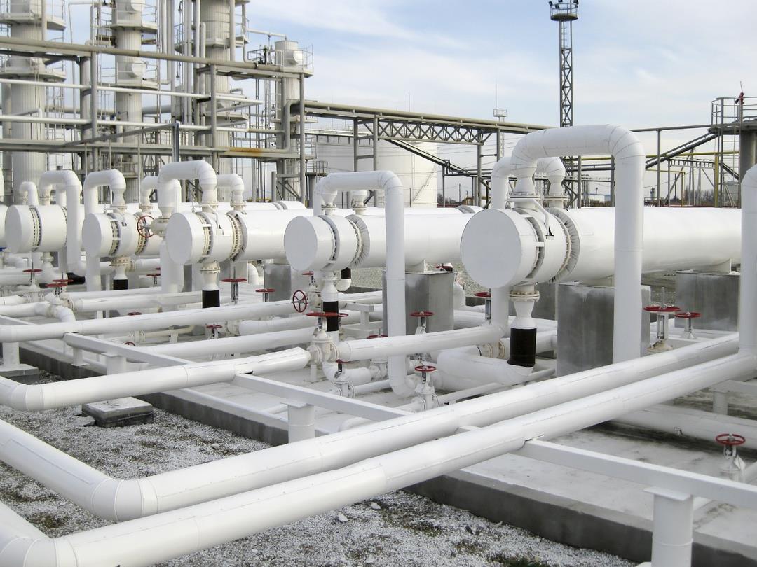 Heat exchangers at an oil refinery. The tanks are long, narrow, white cylinders, with pipes coming from them in geometric…