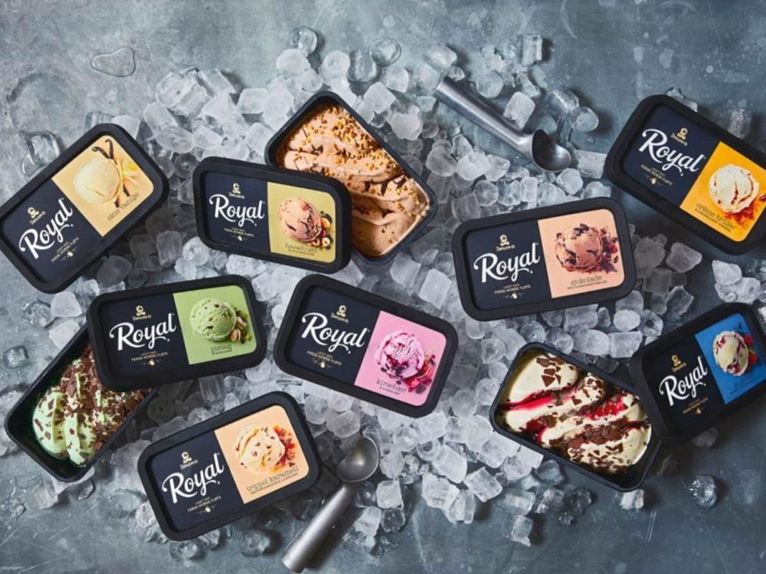 A large pile of ice cubes has been arranged on a metal surface. On top of it are two ice cream scoopers in amongst various…