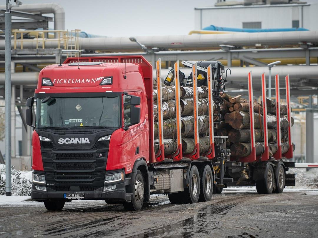 A red Eickelmann truck carries wood timber into UPM's biorefinery construction site.