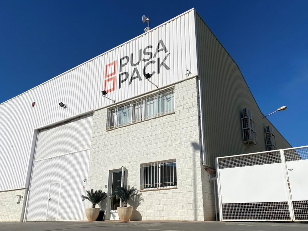 An exterior shot of Pusa Pack's liner bag plant. It is a white building with grates on the windows and the Pusa Pack logo…