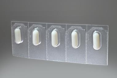 Five prescription pills are packaged in plastic blister packaging against a grey background.
