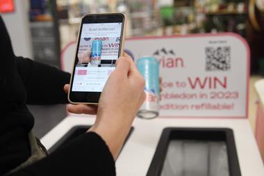 Two hands are visible to the camera. The left is holding an evian can at arm’s length; the other is holding a smartphone and using it to scan a barcode on the can. The can is being held over an evian-branded recycling bin in a Sainsbury’s supermarket.