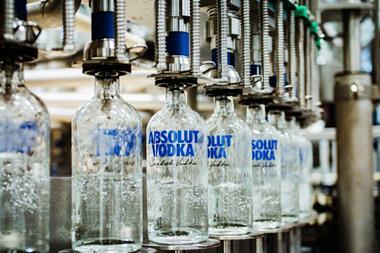 A series of glass bottled labelled 'Absolut Vodka, Swedish Vodka' are being filled with vodka on a factory line.
