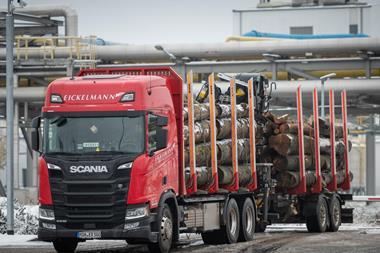 A red Eickelmann truck carries wood timber into UPM's biorefinery construction site.