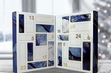 A thick advent calendar folds in the middle to create a compact box. It is propped open to reveal a series of white and blue 'windows', each one labelled with a number corresponding with a day in December.