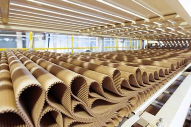 A row of pleat corrugated cardboard lays on a wooden pallet at a factory.