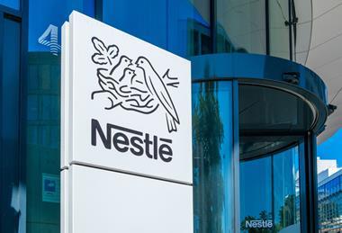 A sign with the Nestle logo against the background of a corporate building.