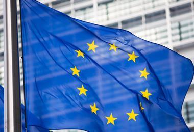 The flag of the European Union, flying in front of the EU parliament building.