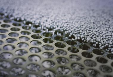 A picture of plastic granules about to be sorted on a perforated screen