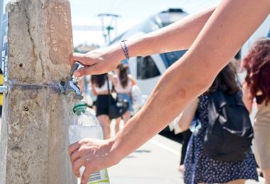 A person filling up a plastic bottle at a public water tap