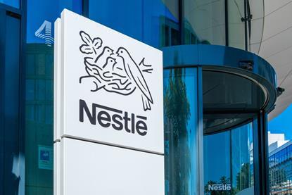 A sign with the Nestle logo against the background of a corporate building.