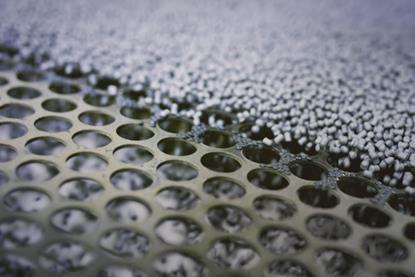 A picture of plastic granules about to be sorted on a perforated screen