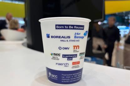 A picture of a reusable cup on a table, the cup has logos of the participating companies on it.