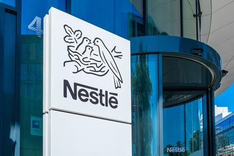 A sign with the Nestle logo against the background of a corporate building.