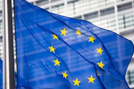 The flag of the European Union, flying in front of the EU parliament building.