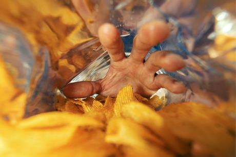 A hand reaching inside of a crisp packet