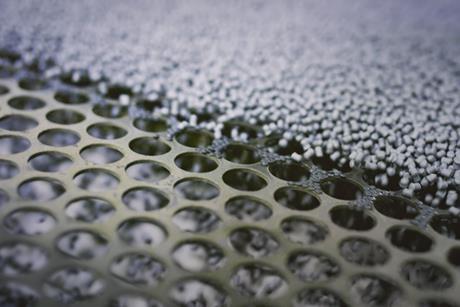 A picture of plastic granules about to be sorted on a perforated screen