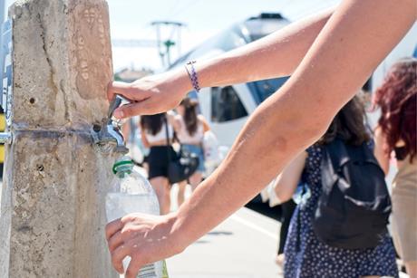 A person filling up a plastic bottle at a public water tap