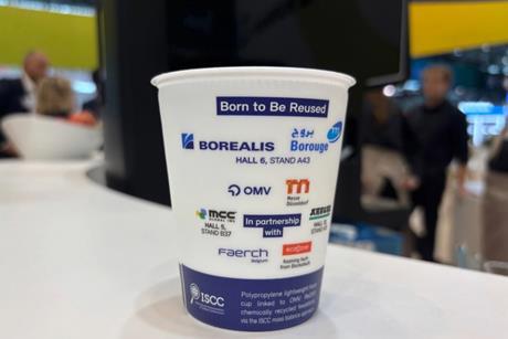 A picture of a reusable cup on a table, the cup has logos of the participating companies on it.