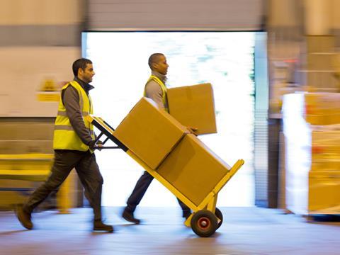 Workers in a warehouse transporting cardboard boxes on a parcel trolley