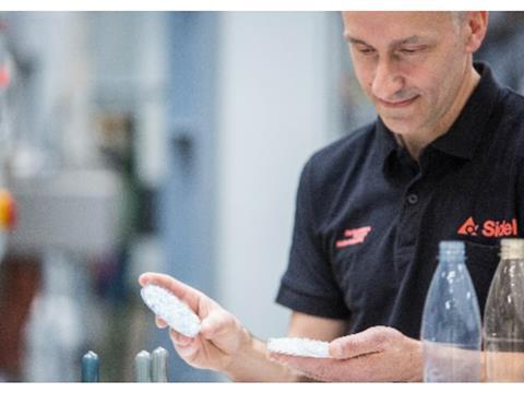 A man is observing two petri dishes containing plastic pellets.