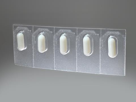 Five prescription pills are packaged in plastic blister packaging against a grey background.