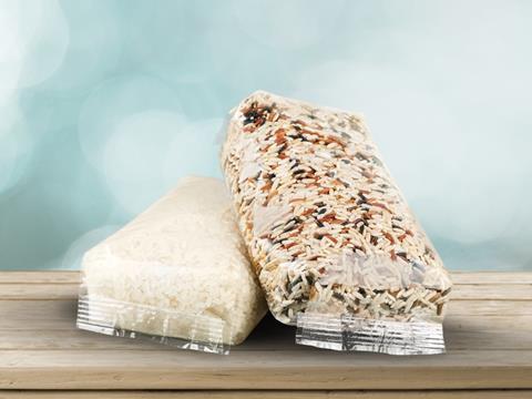 Two packs of white and mixed rice wrapped in flexible plastic packaging sit on a wooden surface.