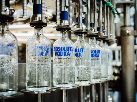 A series of glass bottled labelled 'Absolut Vodka, Swedish Vodka' are being filled with vodka on a factory line.