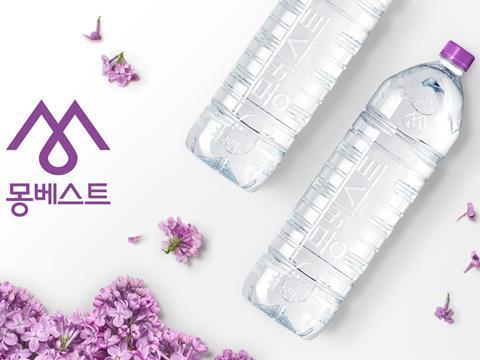 The Montbest logo appears in purple on the left-hand side of the image, with the company name written in Korean beneath it. Purple flowers are sprinkled over a white surface; within them lay two embossed plastic water bottles with purple lids.