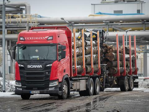 A red Eickelmann truck carries wood timber into UPM's biorefinery construction site.