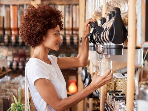 A woman is refilling a glass jar with dry food.