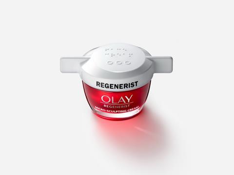 A red, glass container of Olay Regenerist Micro-Sculpting Cream with a white, plastic lid featuring a wing on either side. The lid of the container reads ‘REGENERIST’ in bold black writing, with braille and three circles embossed above it.